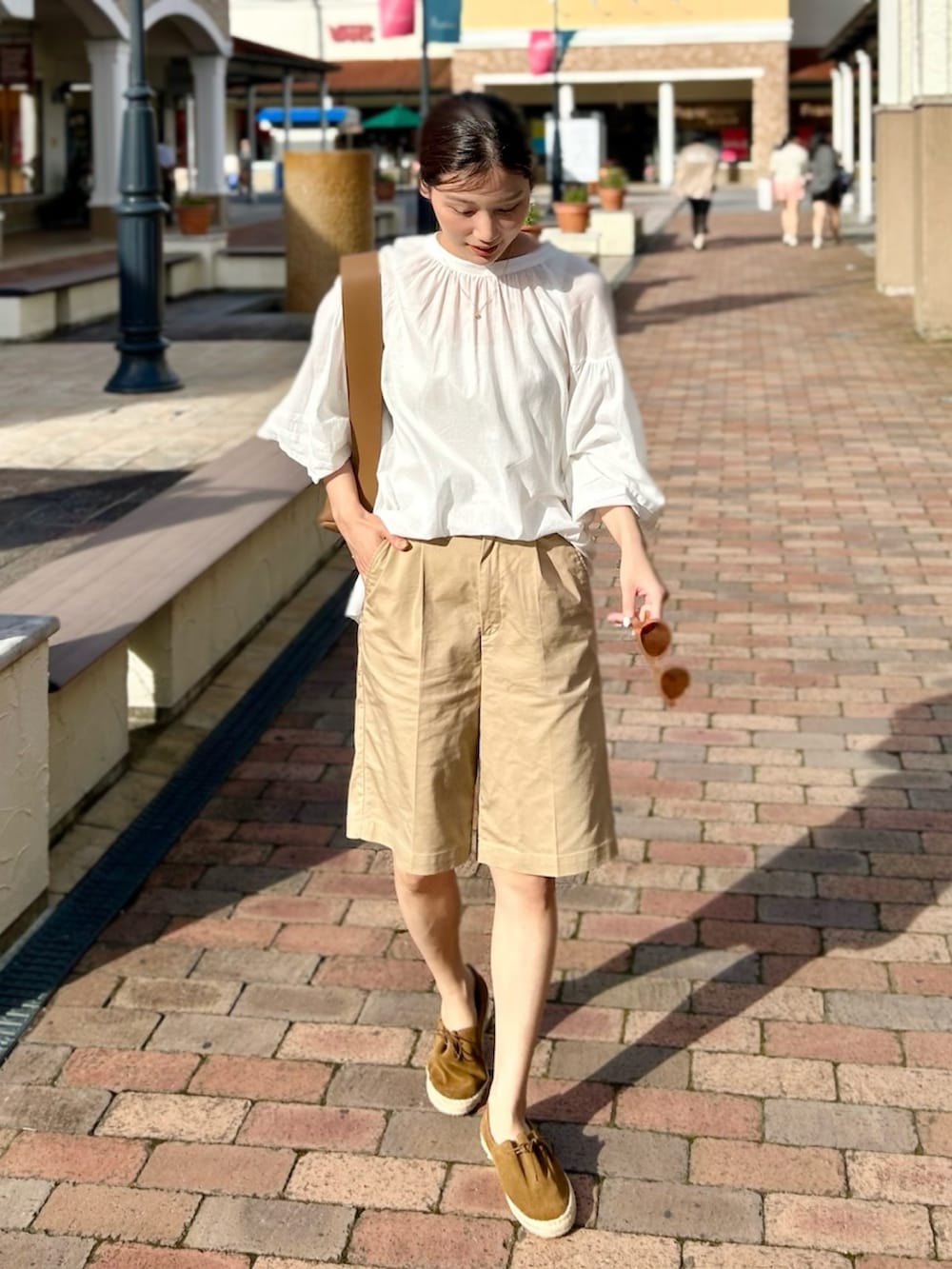 ホワイト系のシャツ/ブラウス、ベージュ系のパンツ、ブラック系のサンダルを着用したレディースの夏コーディネートの2枚目の写真