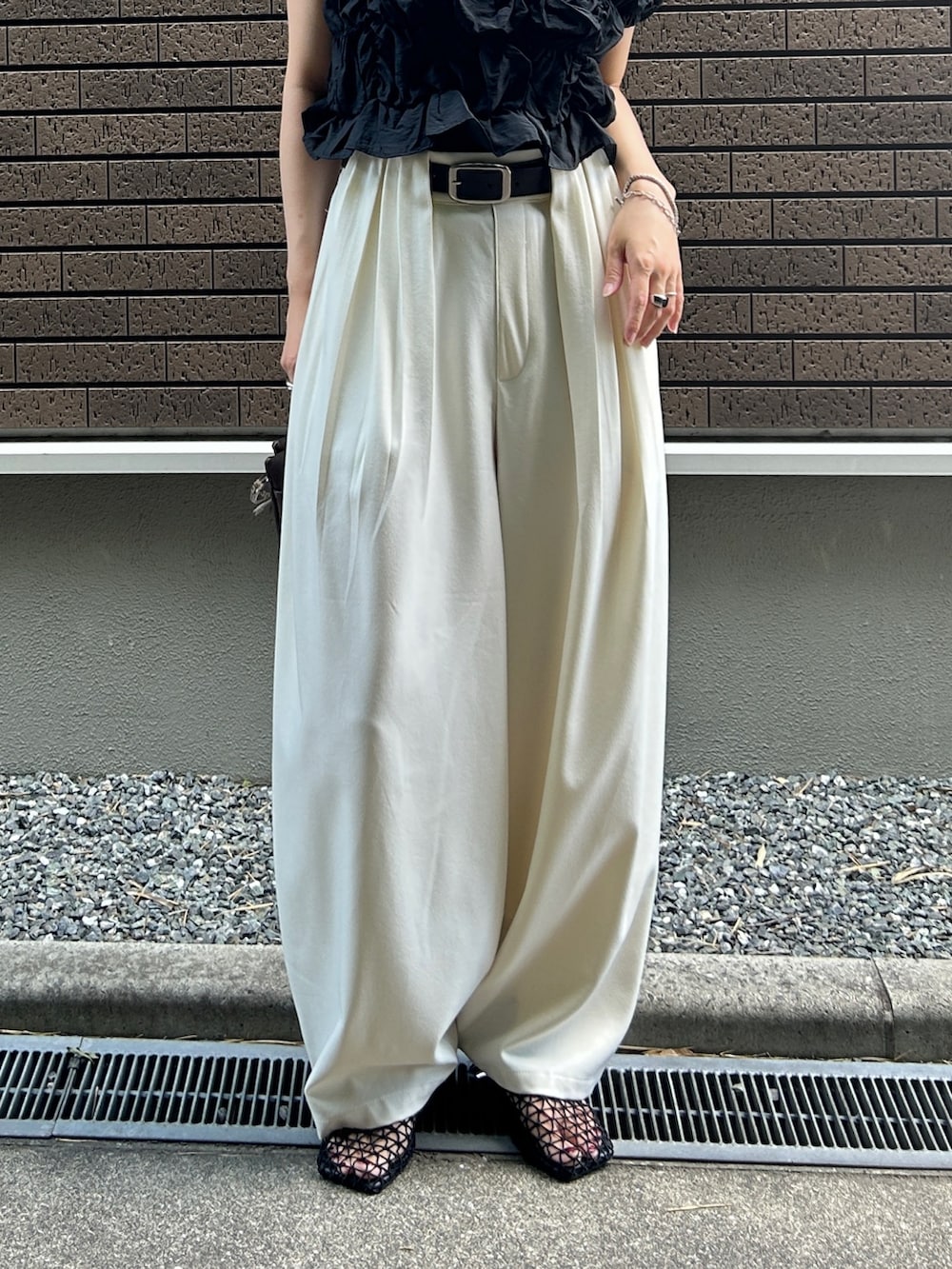 ブラック系のシャツ/ブラウス、ホワイト系のスラックス、ブラウン系のショルダーバッグを着用したレディースの夏コーディネートの5枚目の写真