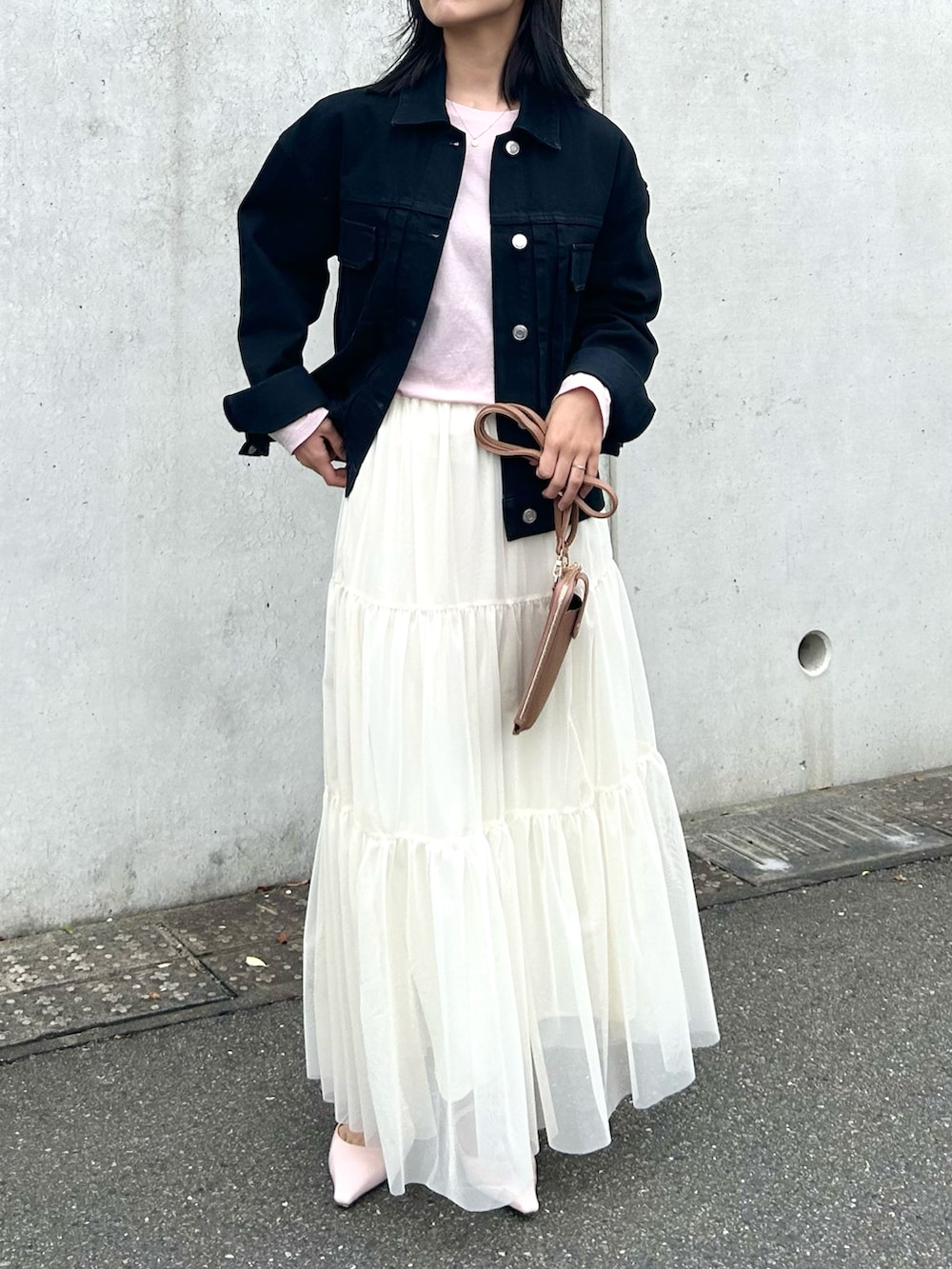ブラック系のデニムジャケット、ホワイト系のスカート、ピンク系のその他シューズを着用したレディースの春コーディネートの2枚目の写真