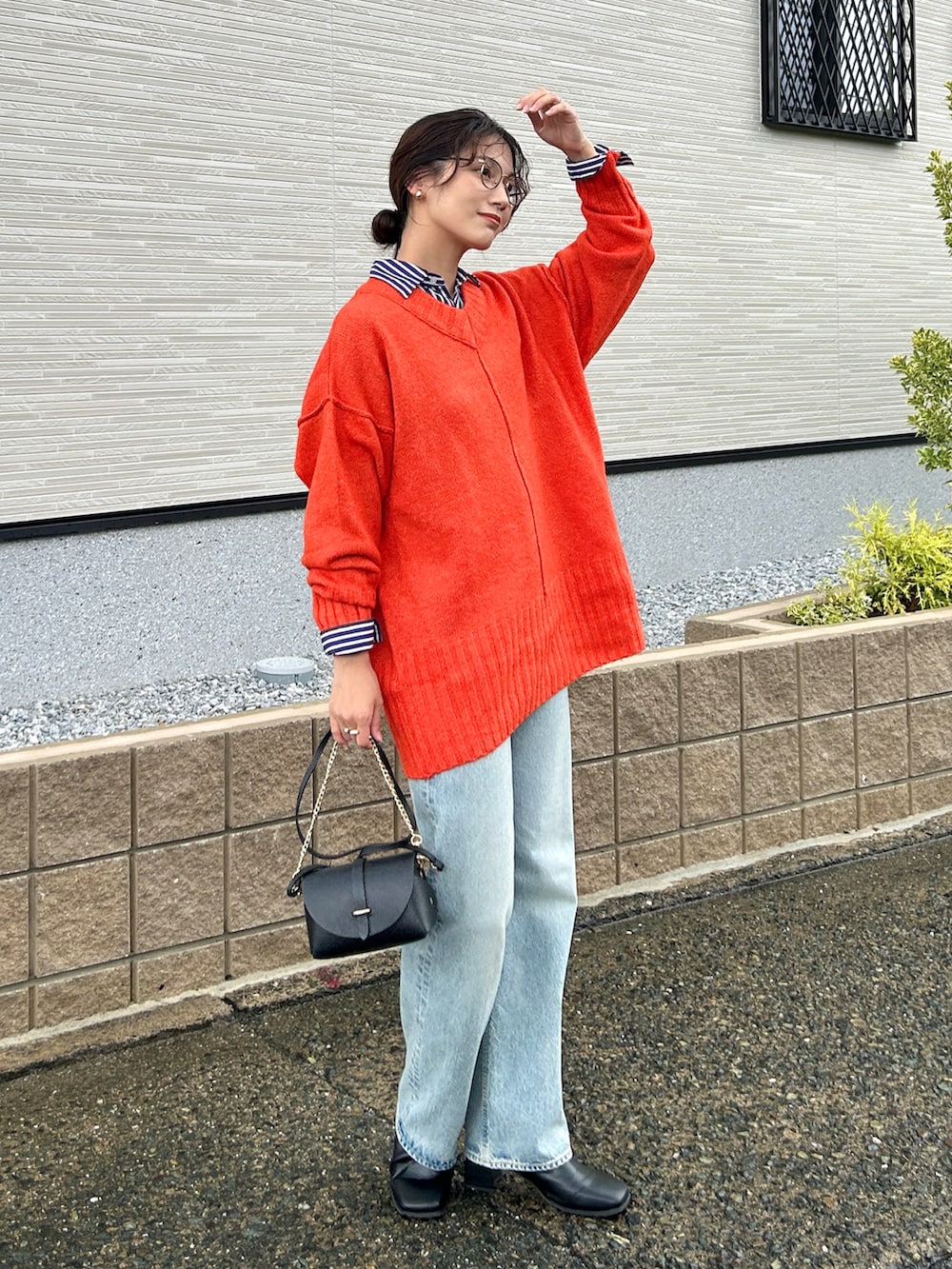 オレンジ系のニット/セーター、ブルー系のシャツ/ブラウス、ブルー系のデニムパンツを着用したレディースの秋コーディネートの3枚目の写真