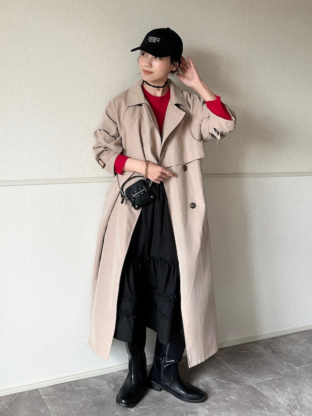 ベージュ系のトレンチコート、ブラック系のスカート、ブラック系のブーツを着用したレディースの春コーディネートの3枚目の写真