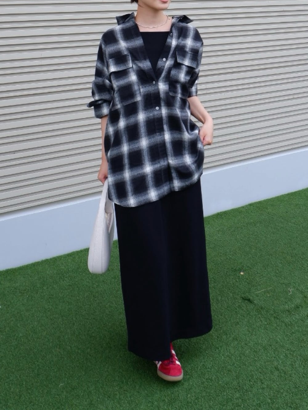 ブラック系のシャツ/ブラウス、ブラック系のワンピース、レッド系のスニーカーを着用したレディースの秋コーディネートの2枚目の写真