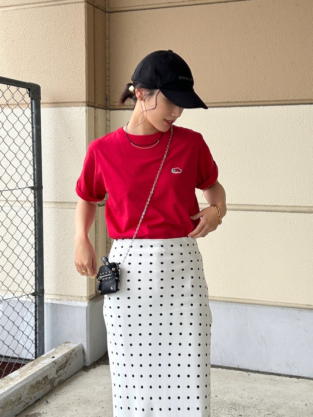 レッド系のTシャツ/カットソー、ホワイト系のスカート、ブラック系のパンプスを着用したレディースの春コーディネートの2枚目の写真