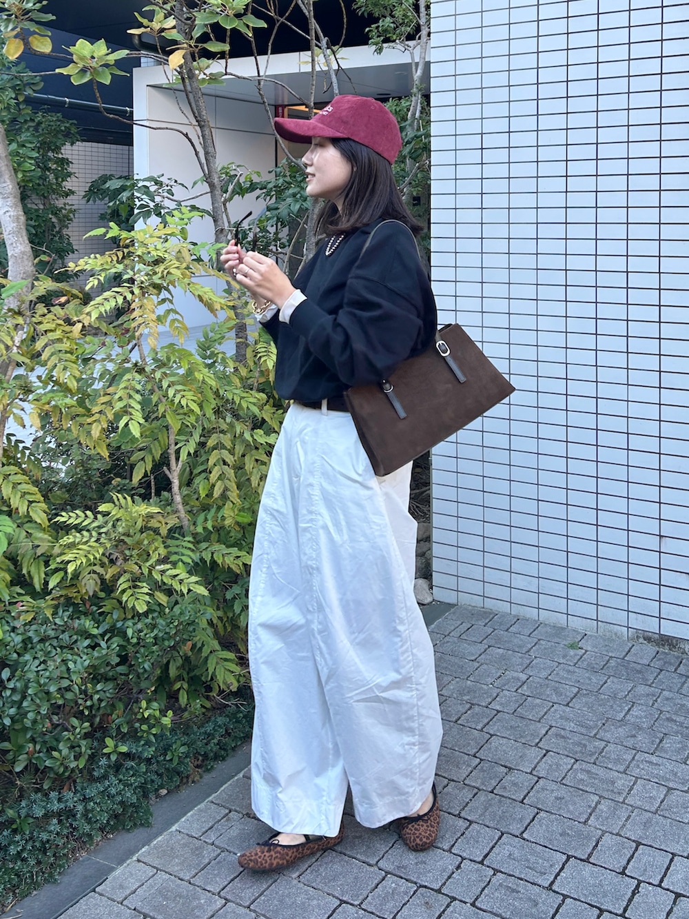 グリーン系のハンドバッグ、ホワイト系のその他パンツ、ゴールド系のブレスレットを着用したレディースの秋コーディネートの2枚目の写真