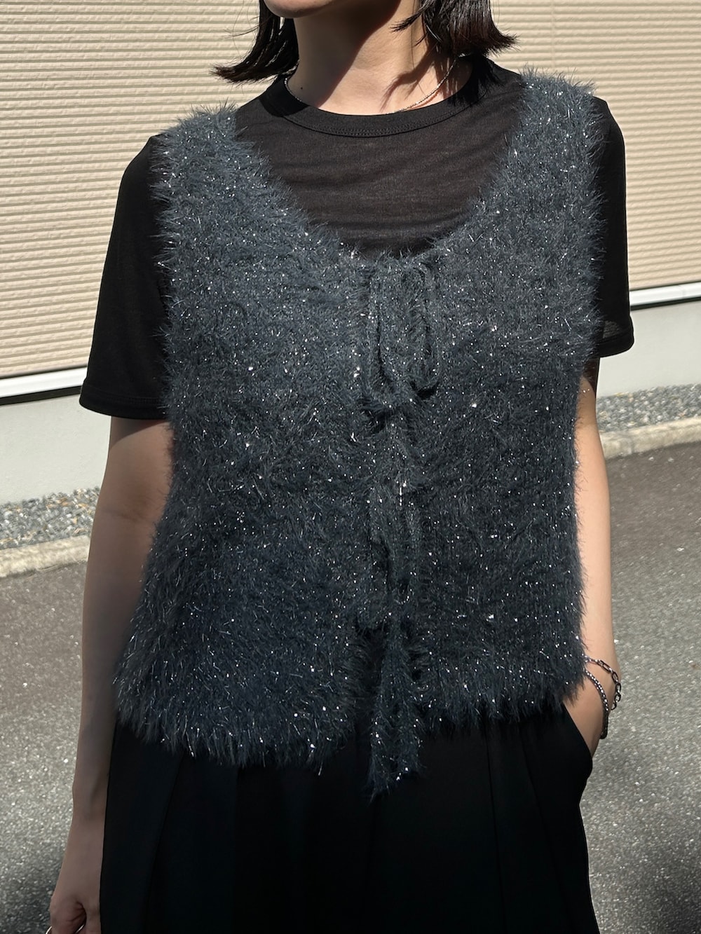 グレー系のベスト、ブラック系のボストンバッグ、ブラック系のサンダルを着用したレディースの夏コーディネートの2枚目の写真