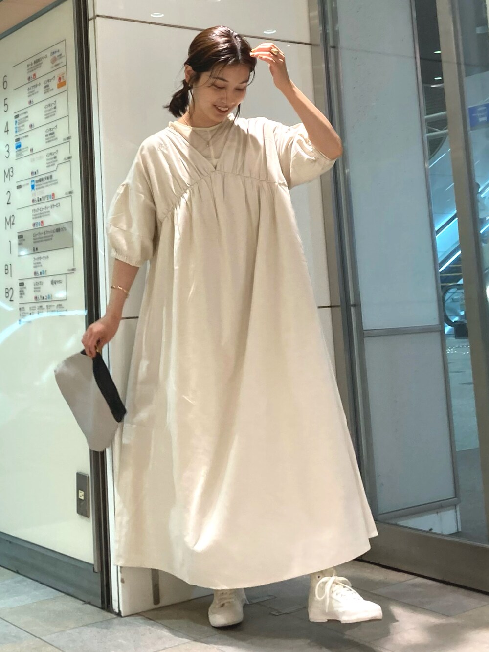 ブラック系のバッグ、ホワイト系のワンピース、ホワイト系のスニーカーを着用したレディースの春コーディネートの2枚目の写真