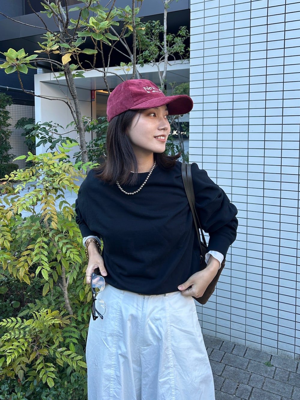 グリーン系のハンドバッグ、ホワイト系のその他パンツ、ゴールド系のブレスレットを着用したレディースの秋コーディネートの3枚目の写真