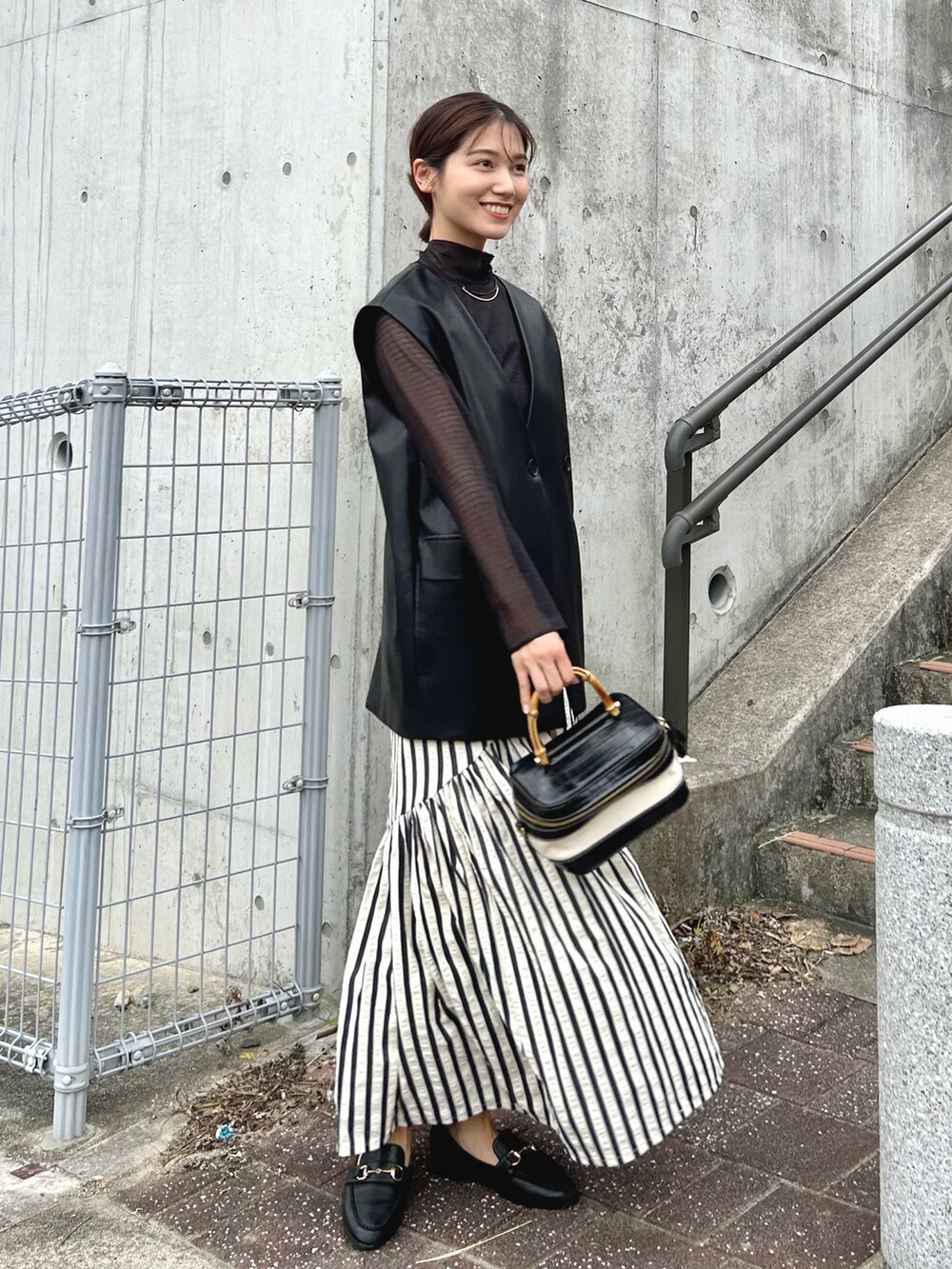 ブラック系のトップス、ブラック系のキャミソール、ブラック系のベストを着用したレディースの秋コーディネートの3枚目の写真