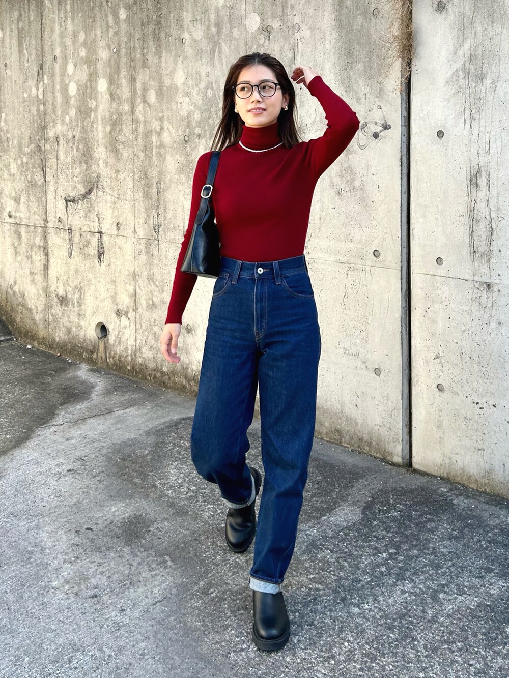 レッド系のニット/セーター、ブルー系のデニムパンツ、ブラック系のハンドバッグを着用したレディースの秋コーディネートの2枚目の写真