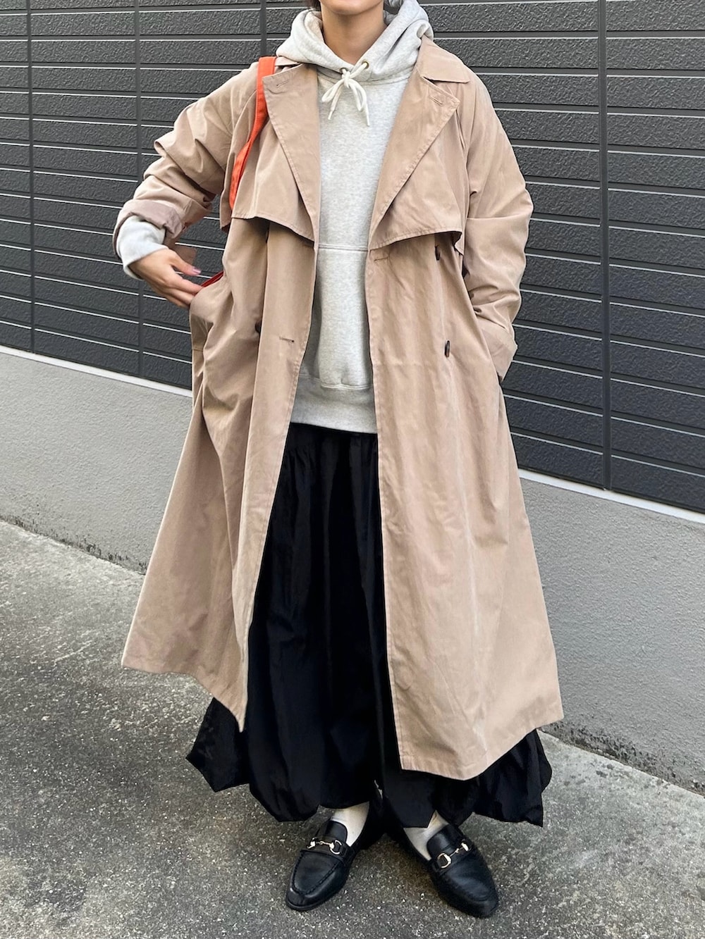 ベージュ系のトレンチコート、グレー系のパーカー、ブラック系のスカートを着用したレディースの春コーディネートの3枚目の写真