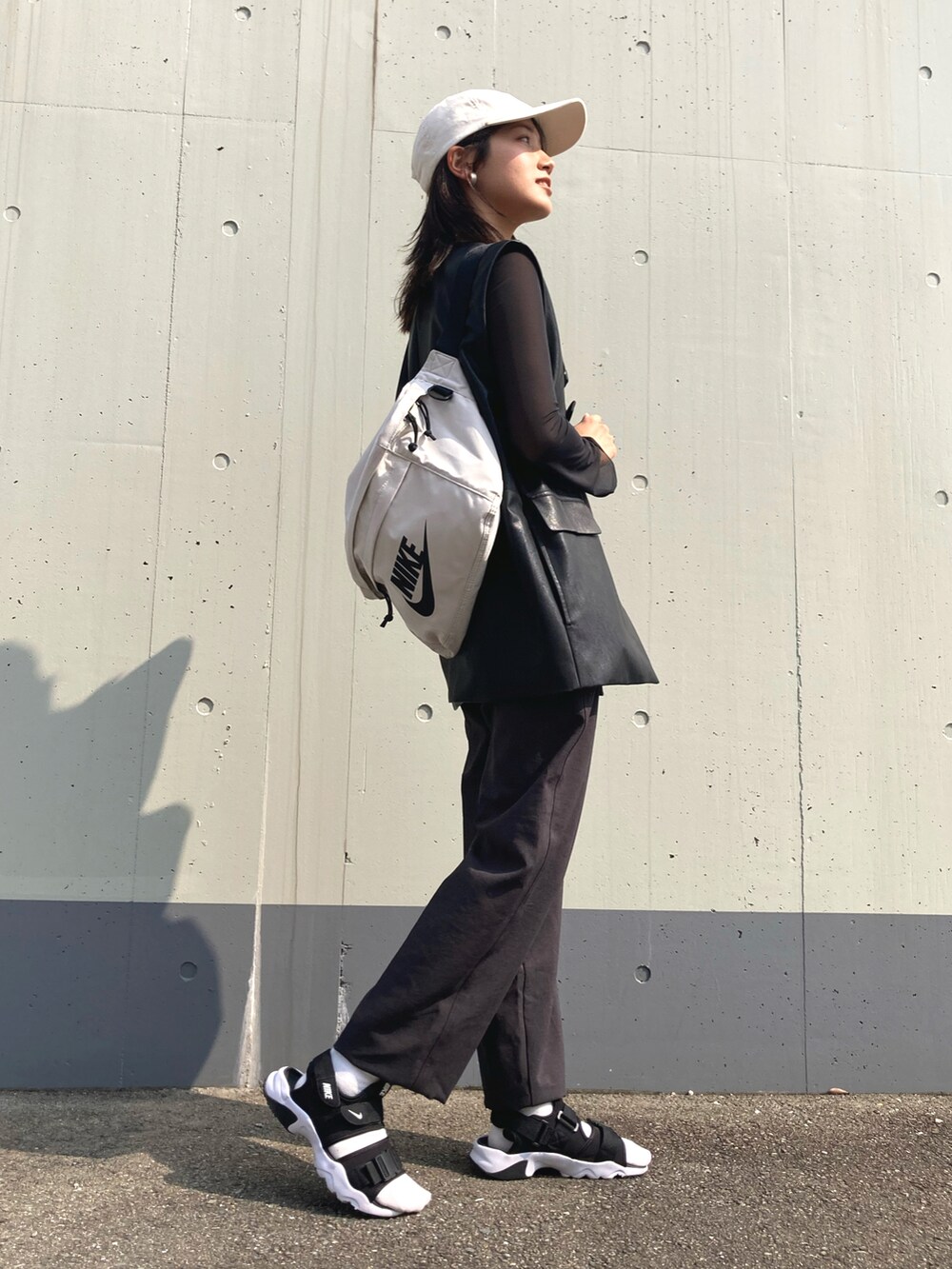 グレー系のパンツ、ブラック系のベスト、ブラック系のTシャツ/カットソーを着用したレディースの春コーディネートの3枚目の写真
