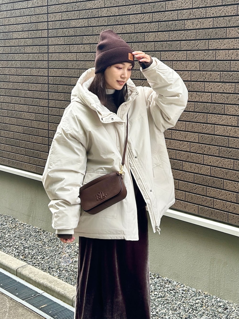 ホワイト系のブルゾン、ブラック系のブーツ、ブラウン系のニット/セーターを着用したレディースの冬コーディネートの5枚目の写真