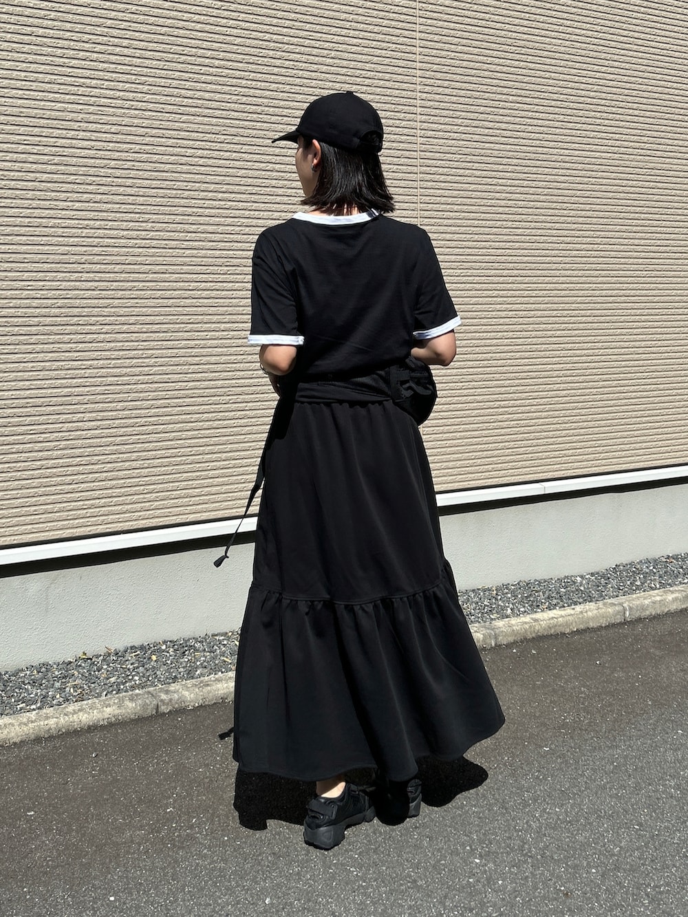 ブラック系のスニーカー、ブラック系のTシャツ/カットソー、ブラック系のスカートを着用したレディースの夏コーディネートの2枚目の写真