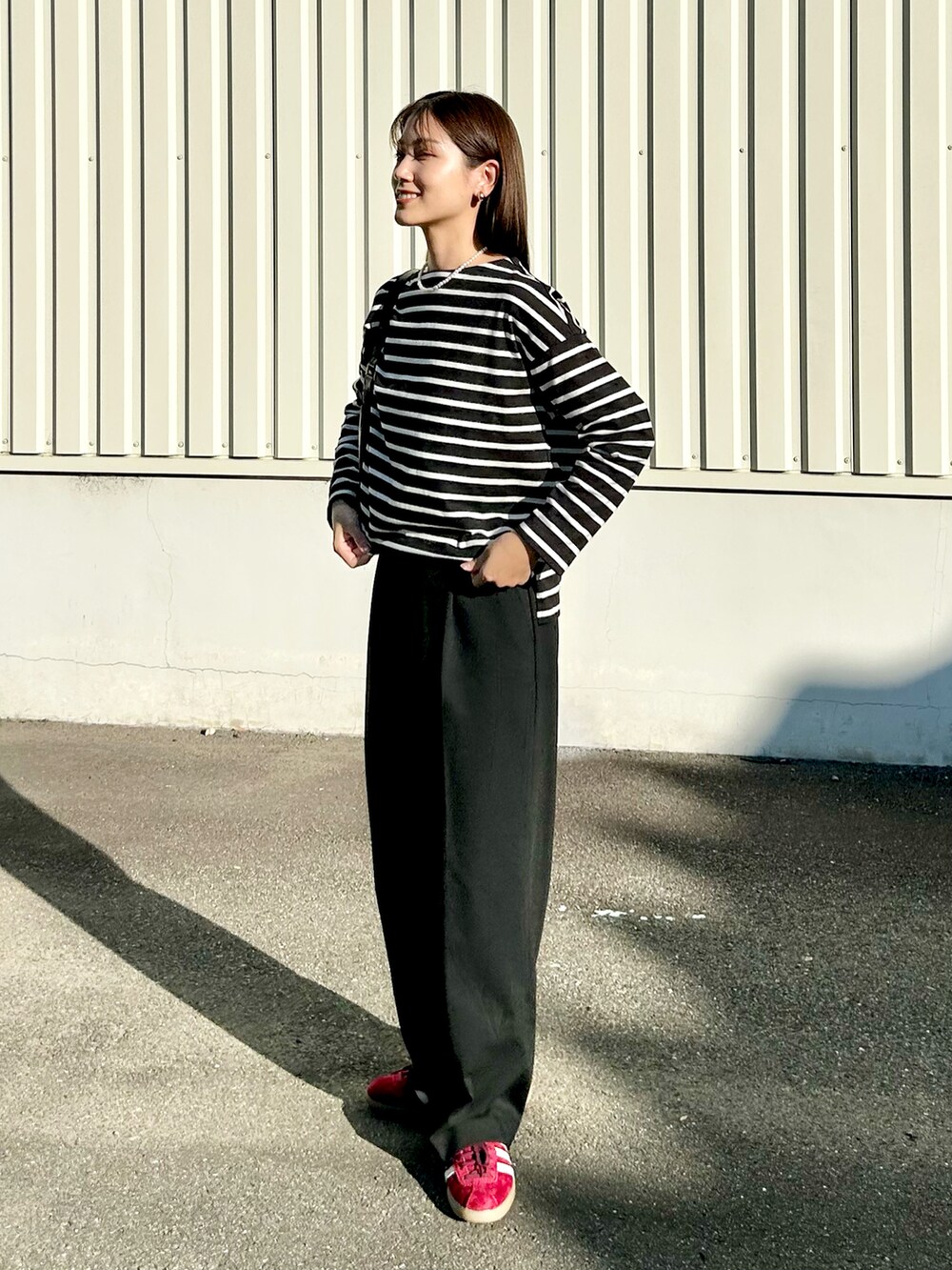 ブラック系のトップス、ブラック系のスラックス、レッド系のスニーカーを着用したレディースの秋コーディネートの3枚目の写真