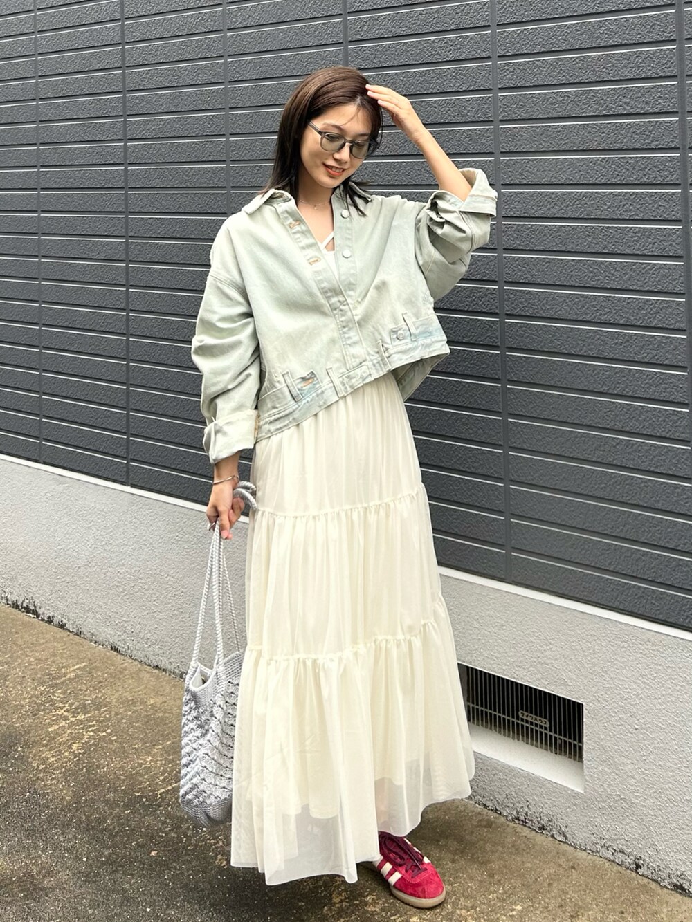 ブルー系のデニムジャケット、ホワイト系のキャミソール、ホワイト系のスカートを着用したレディースの春コーディネートの2枚目の写真