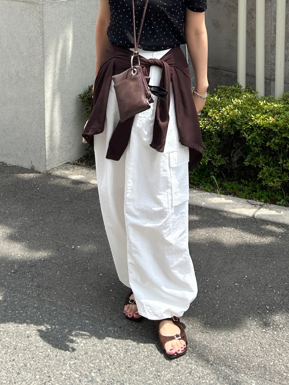 ホワイト系のカーゴパンツ、ブラック系のTシャツ/カットソー、ブラウン系のショルダーバッグを着用したレディースの夏コーディネートの2枚目の写真