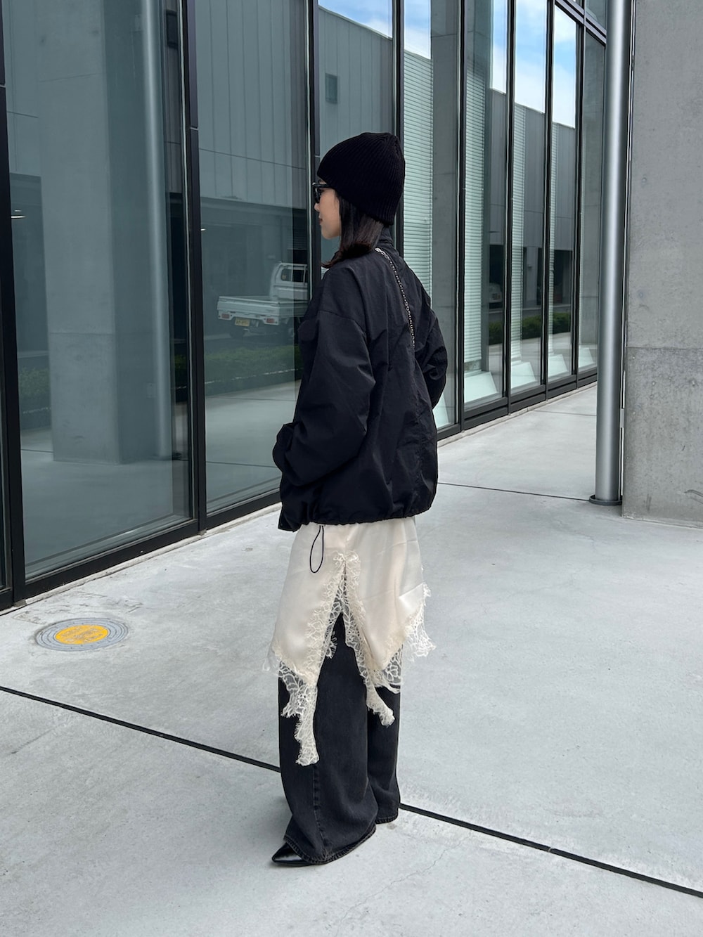 ホワイト系のキャミソール、ブラック系のナイロンジャケット、ブラック系のパンプスを着用したレディースの春コーディネートの3枚目の写真