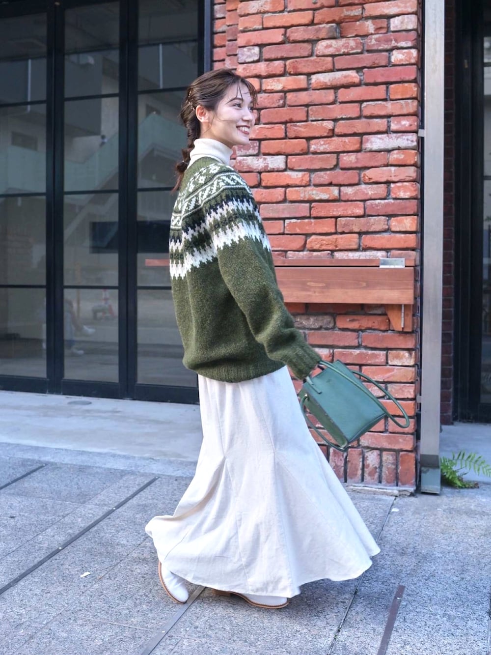 ホワイト系のスカート、グリーン系のニット/セーター、グリーン系のショルダーバッグを着用したレディースの秋コーディネートの2枚目の写真
