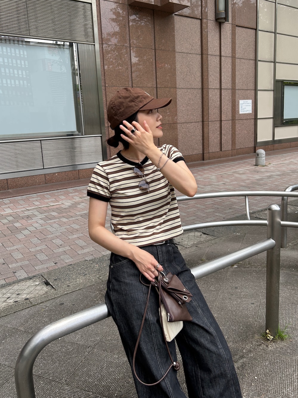 ブラック系のスニーカー、ホワイト系のTシャツ/カットソー、ブラウン系のショルダーバッグを着用したレディースの夏コーディネートの2枚目の写真