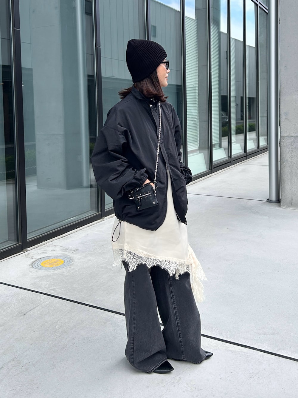 ホワイト系のキャミソール、ブラック系のナイロンジャケット、ブラック系のパンプスを着用したレディースの春コーディネートの4枚目の写真