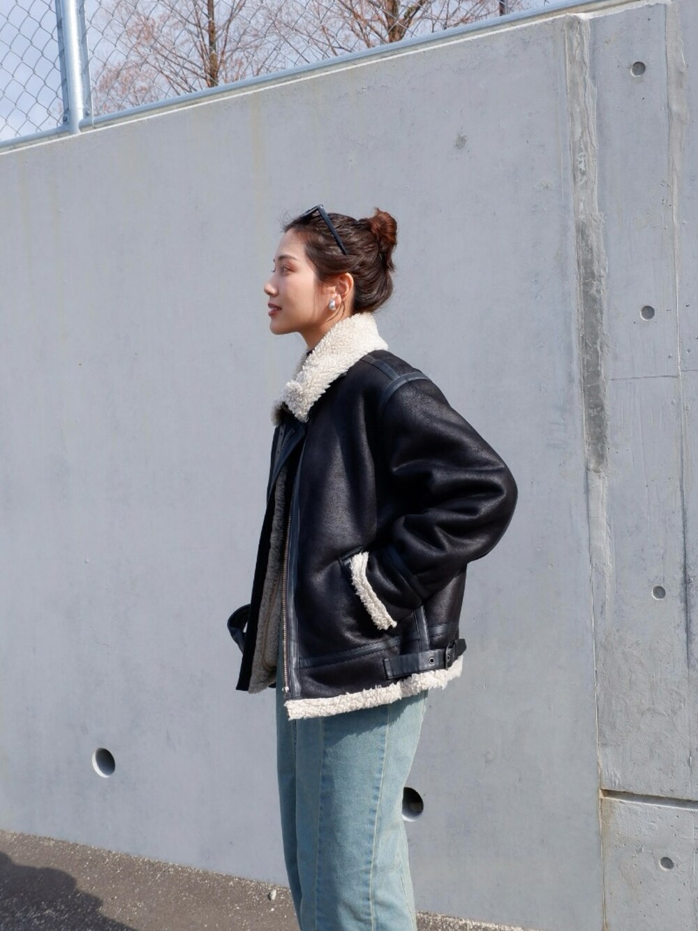 ブルー系のスカート、ブラック系のムートンコート、ブラック系のハンドバッグを着用したレディースの冬コーディネートの3枚目の写真