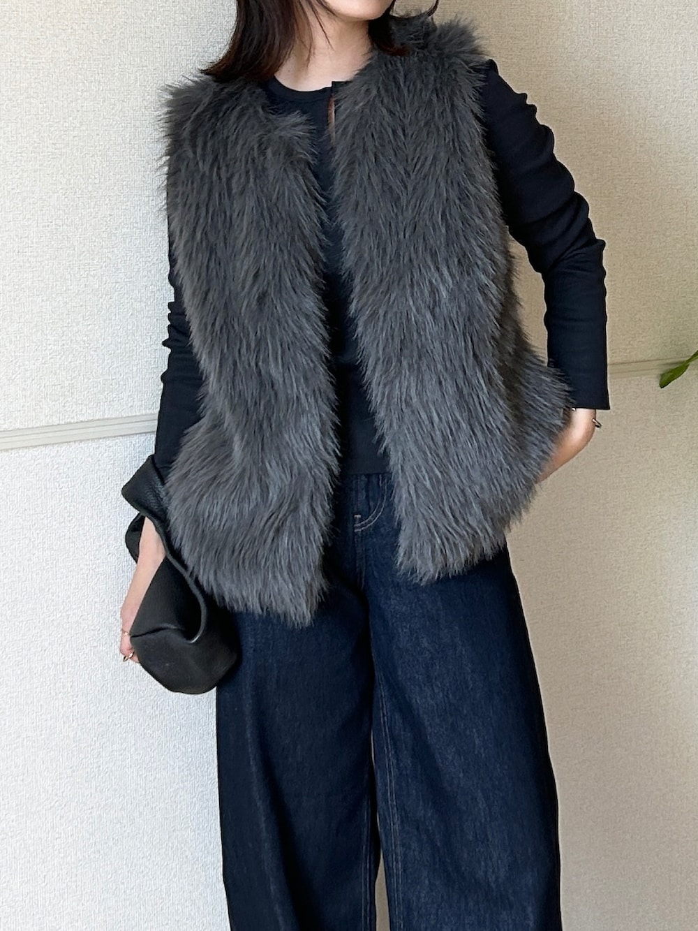 グレー系のベスト、シルバー系のパンプス、ブラック系のハンドバッグを着用したレディースの秋コーディネートの2枚目の写真