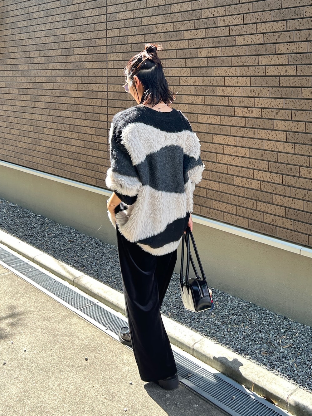 ブラック系のカーディガン/ボレロ、ブラック系のパンツ、ブラック系のローファーを着用したレディースの秋コーディネートの5枚目の写真