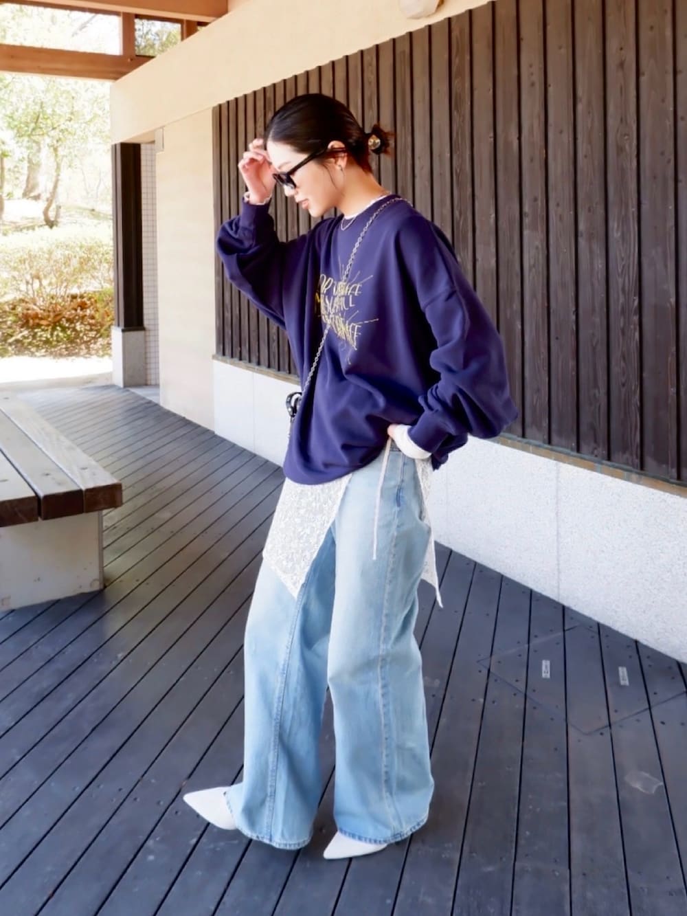 ブルー系のスウェット、ホワイト系のパンプス、ブラック系のポーチを着用したレディースの春コーディネートの4枚目の写真