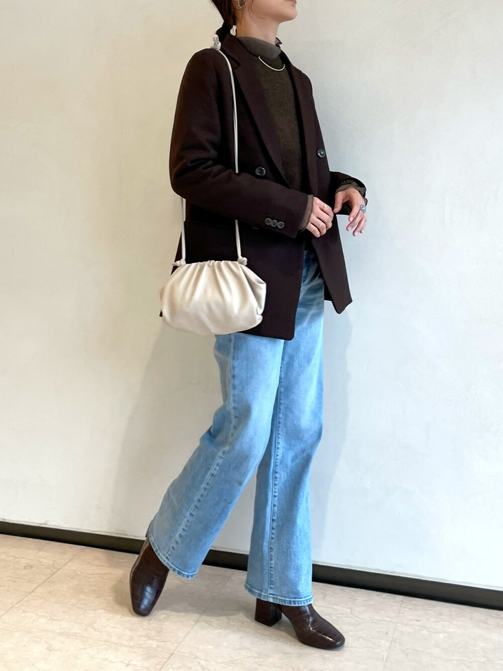ブルー系のデニムパンツ、ブラウン系のテーラードジャケット、ブラウン系のニット/セーターを着用したレディースの春コーディネートの3枚目の写真