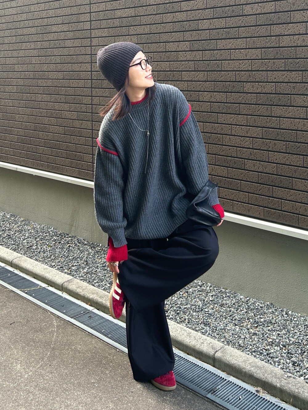 グレー系のニット/セーター、ブラック系のハンドバッグ、ブラック系のスラックスを着用したレディースの秋コーディネートの2枚目の写真