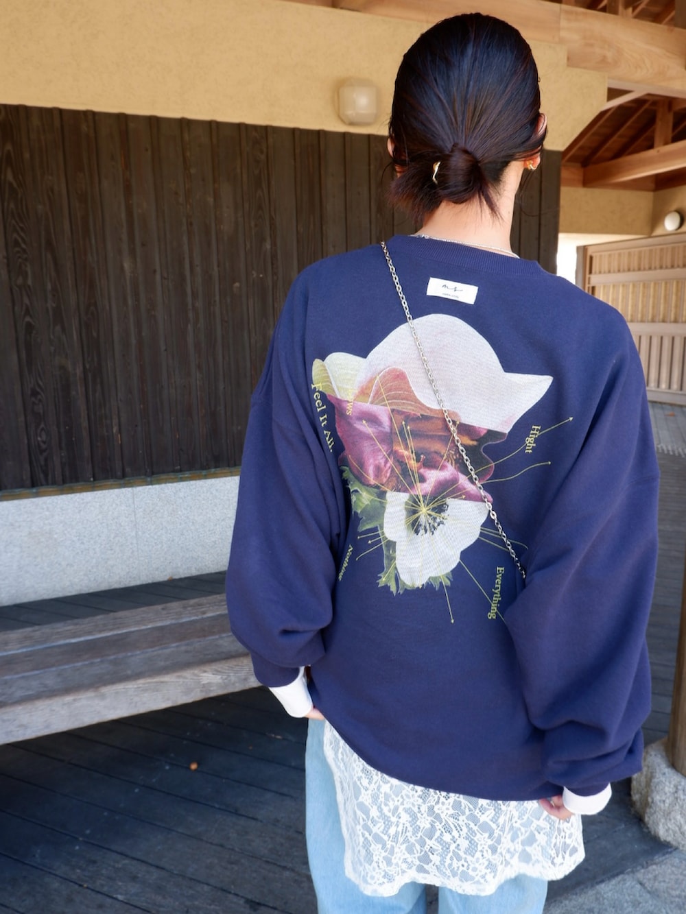 ブルー系のスウェット、ホワイト系のパンプス、ブラック系のポーチを着用したレディースの春コーディネートの2枚目の写真