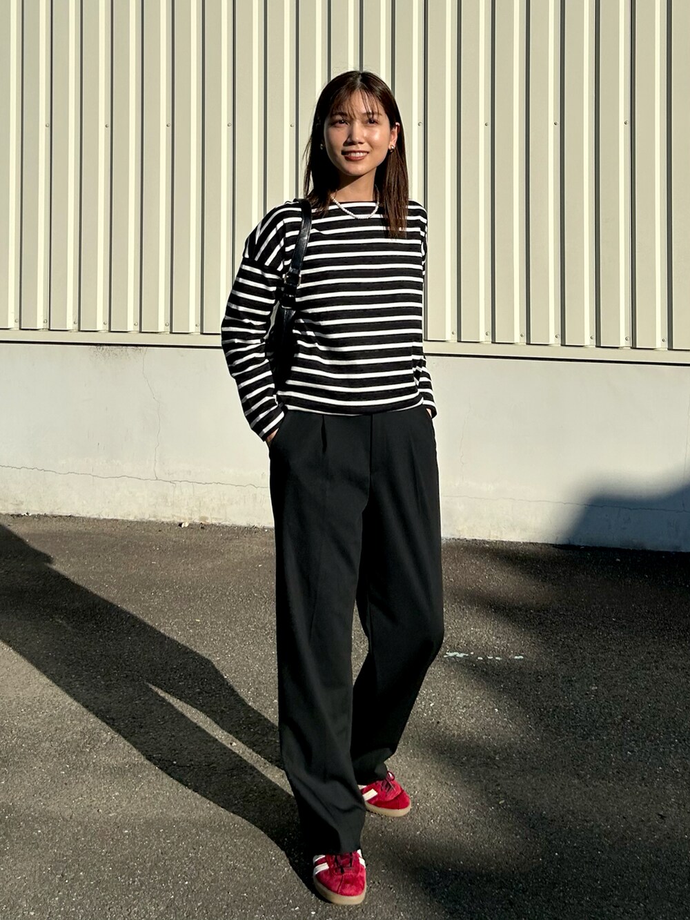 ブラック系のトップス、ブラック系のスラックス、レッド系のスニーカーを着用したレディースの秋コーディネートの2枚目の写真