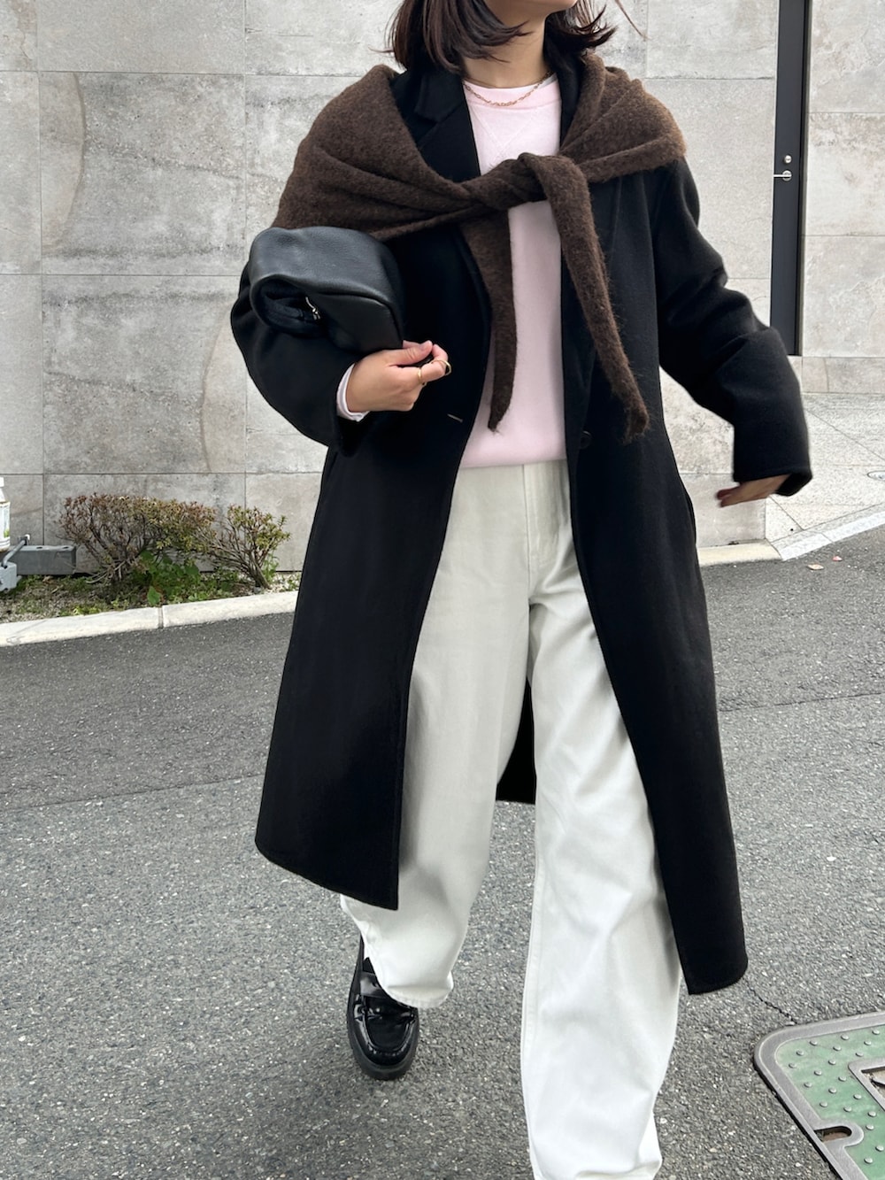 ブラック系のハンドバッグ、ブラック系のジャケット/アウター、ホワイト系のデニムパンツを着用したレディースの冬コーディネートの3枚目の写真