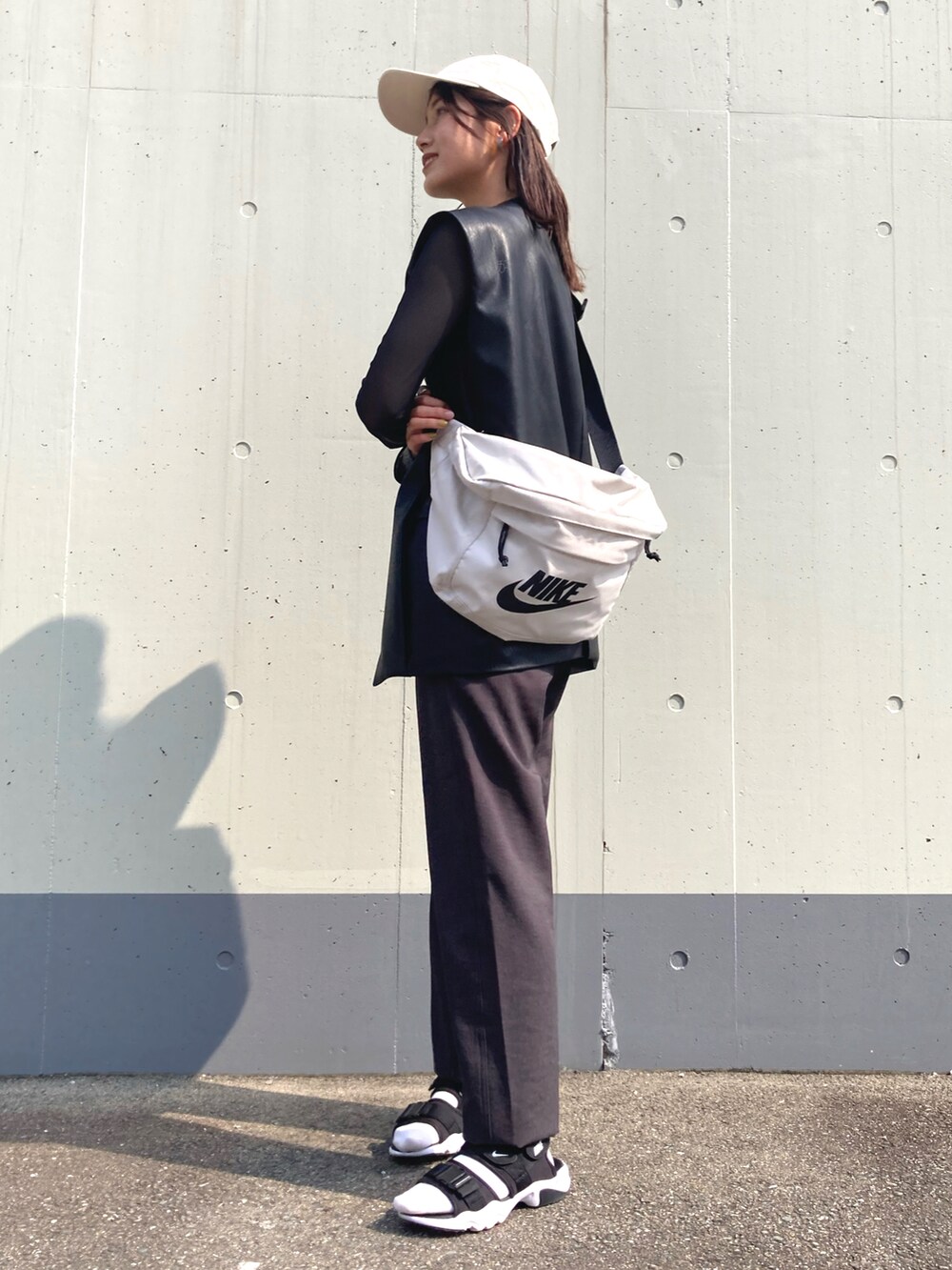 グレー系のパンツ、ブラック系のベスト、ブラック系のTシャツ/カットソーを着用したレディースの春コーディネートの2枚目の写真