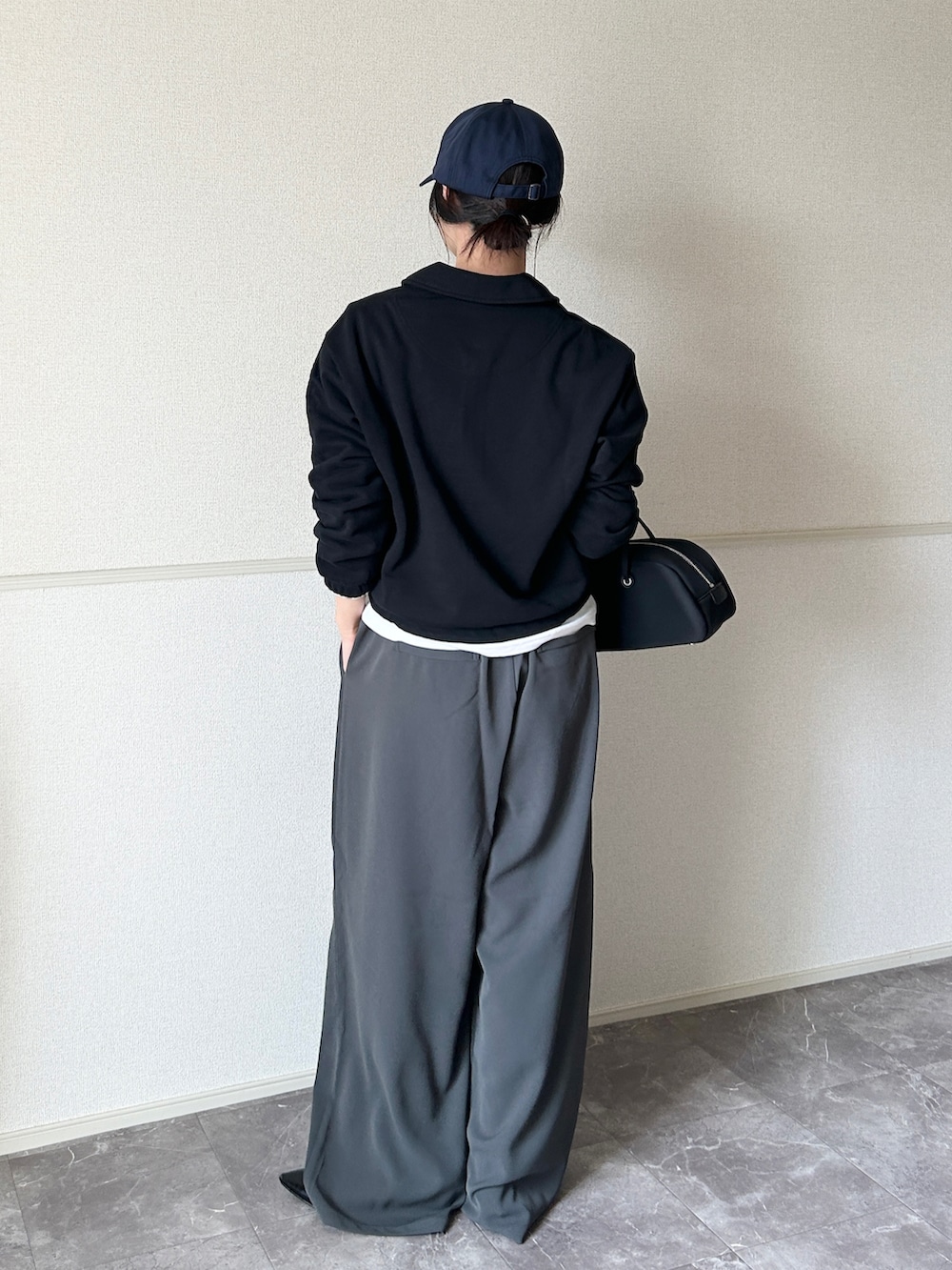 グレー系のスラックス、ブラック系のボストンバッグ、ブラック系のパンプスを着用したレディースの春コーディネートの2枚目の写真