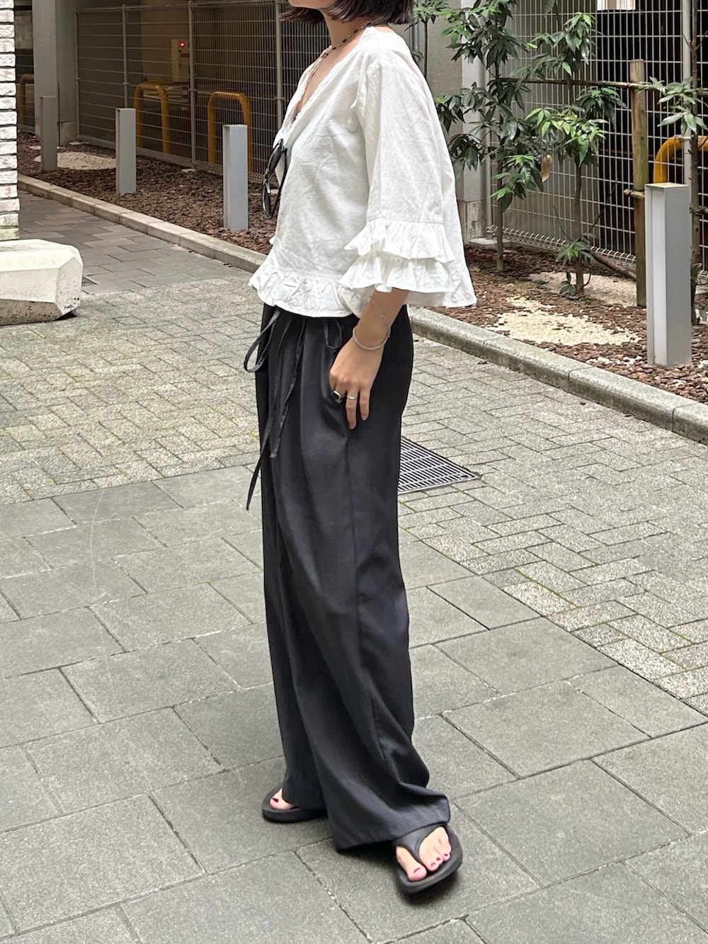 ホワイト系のシャツ/ブラウス、グレー系のその他パンツ、ブラック系のサンダルを着用したレディースの夏コーディネートの2枚目の写真