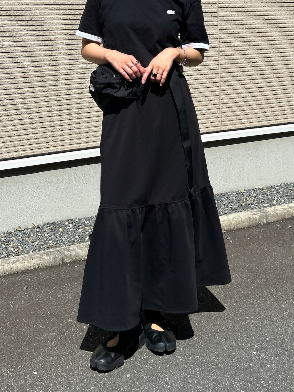 ブラック系のスニーカー、ブラック系のTシャツ/カットソー、ブラック系のスカートを着用したレディースの夏コーディネートの3枚目の写真