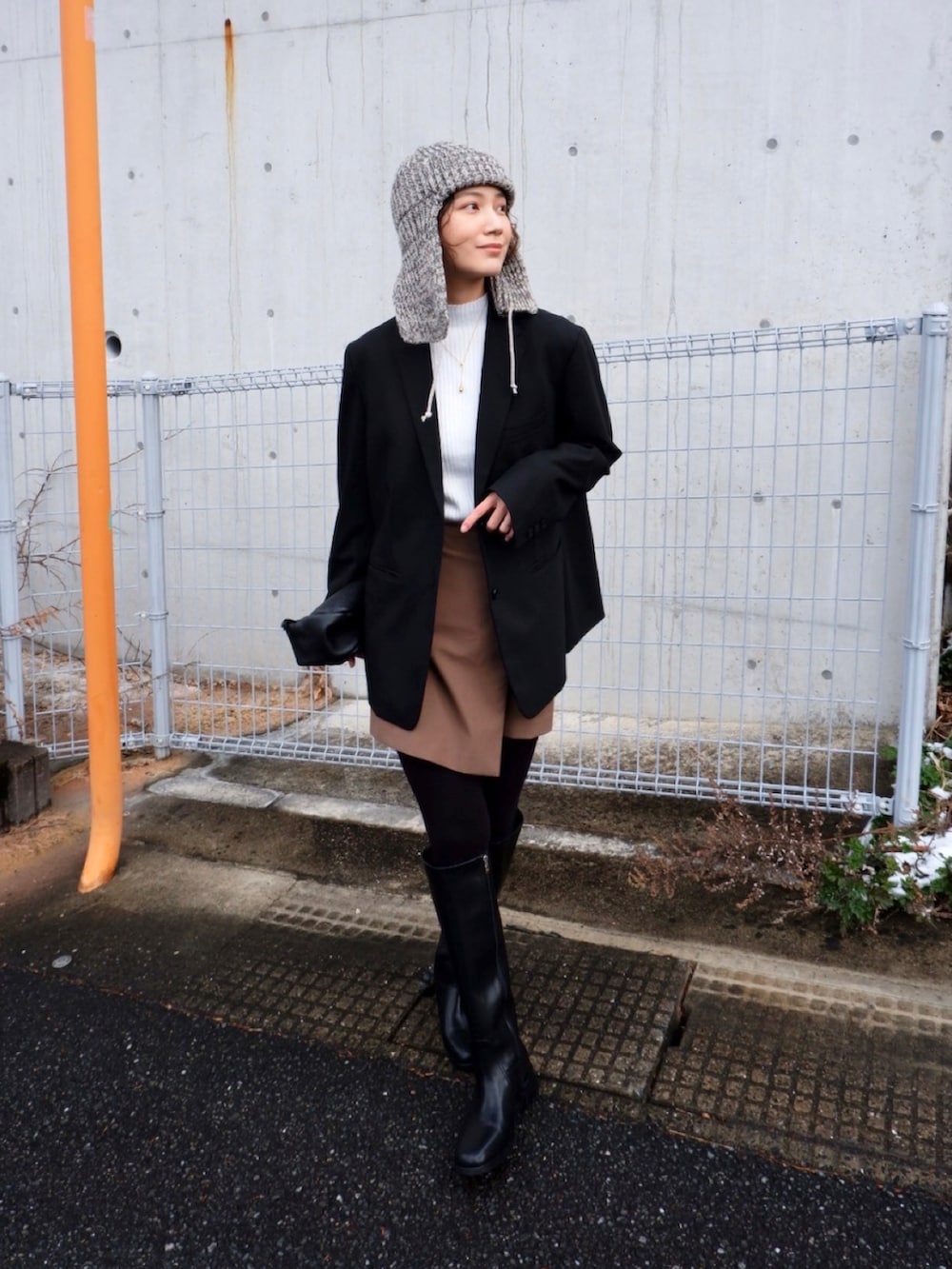 ホワイト系のニット/セーター、ブラウン系のスカート、ブラック系のブーツを着用したレディースの冬コーディネートの2枚目の写真