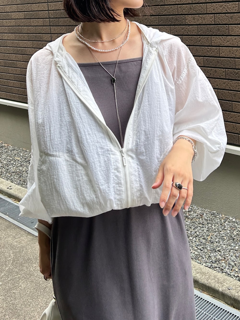 グレー系のワンピース、ホワイト系のマウンテンパーカー、ホワイト系のバッグを着用したレディースの夏コーディネートの4枚目の写真