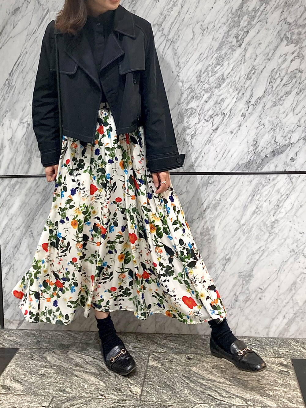 ブラック系のシャツ/ブラウス、ブラック系のトレンチコート、ホワイト系のスカートを着用したレディースの秋コーディネートの2枚目の写真