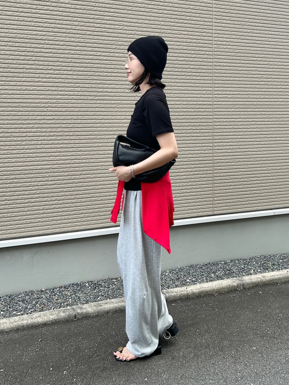 グレー系のスウェットパンツ、ブラック系のサンダル、ブラック系のハンドバッグを着用したレディースの夏コーディネートの3枚目の写真