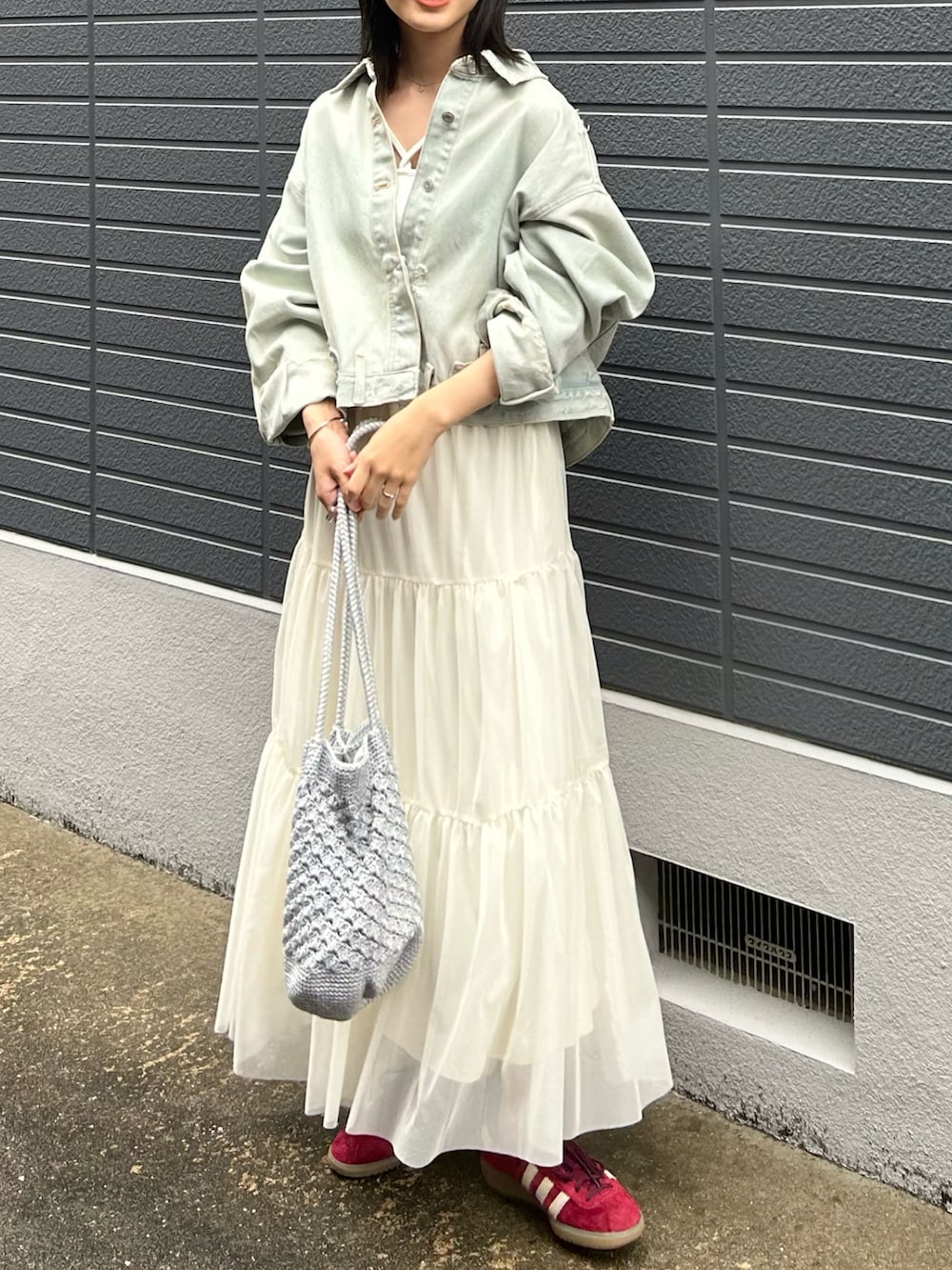 ブルー系のデニムジャケット、ホワイト系のキャミソール、ホワイト系のスカートを着用したレディースの春コーディネートの3枚目の写真