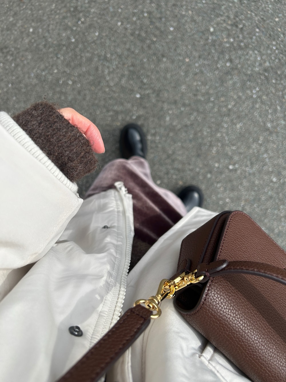 ホワイト系のブルゾン、ブラック系のブーツ、ブラウン系のニット/セーターを着用したレディースの冬コーディネートの2枚目の写真