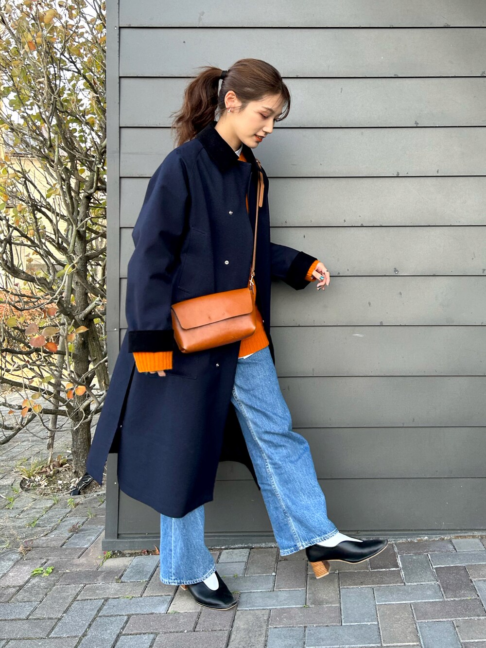 ブラック系のパンプス、オレンジ系のニット/セーター、ブルー系のジャケット/アウターを着用したレディースの冬コーディネートの2枚目の写真