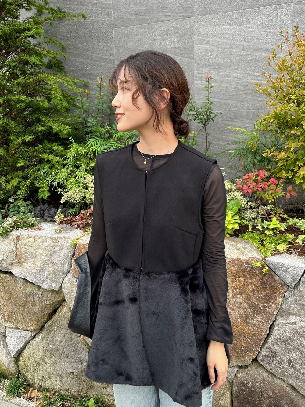 ブラック系のベスト、ブルー系のデニムパンツ、ブラック系のブーツを着用したレディースの秋コーディネートの2枚目の写真