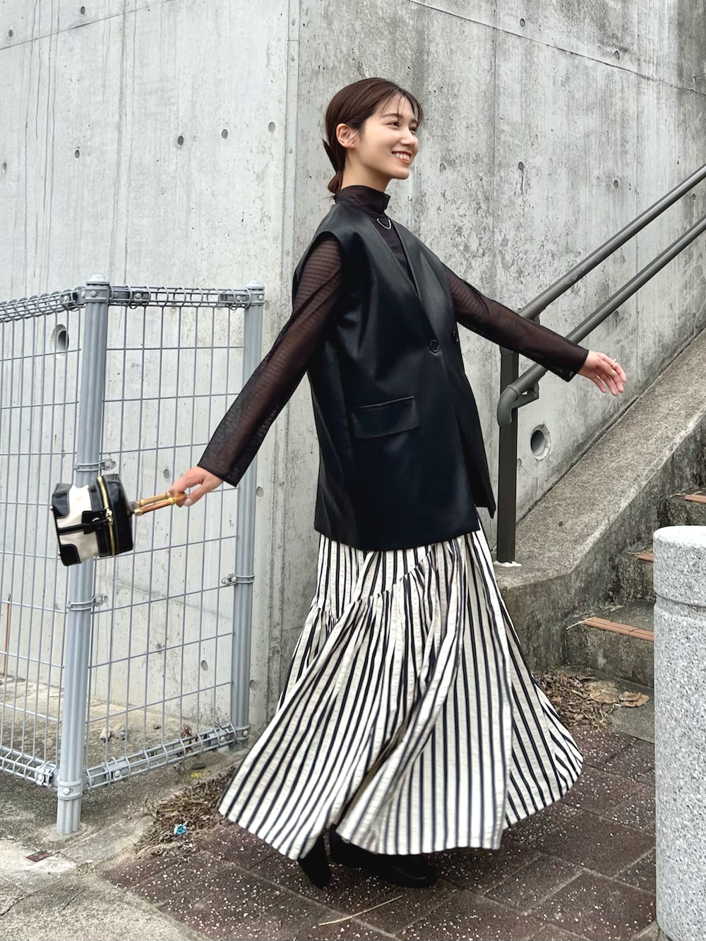 ブラック系のトップス、ブラック系のキャミソール、ブラック系のベストを着用したレディースの秋コーディネートの2枚目の写真