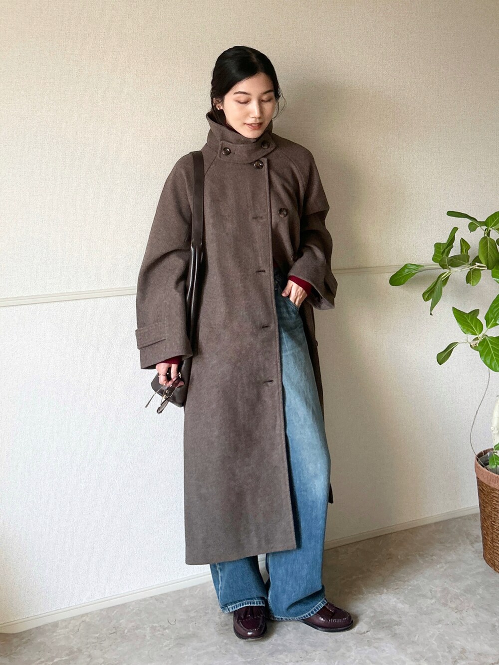 ブラウン系のステンカラーコート、レッド系のローファー、レッド系のニット/セーターを着用したレディースの冬コーディネートの2枚目の写真