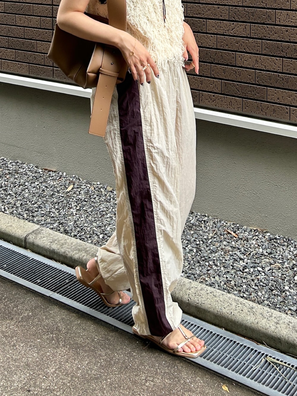 ホワイト系のベスト、ベージュ系のその他パンツ、ブラウン系のショルダーバッグを着用したレディースの夏コーディネートの3枚目の写真