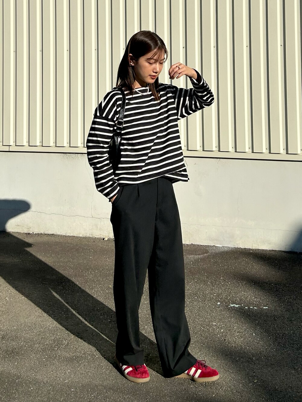 ブラック系のトップス、ブラック系のスラックス、レッド系のスニーカーを着用したレディースの秋コーディネートの5枚目の写真