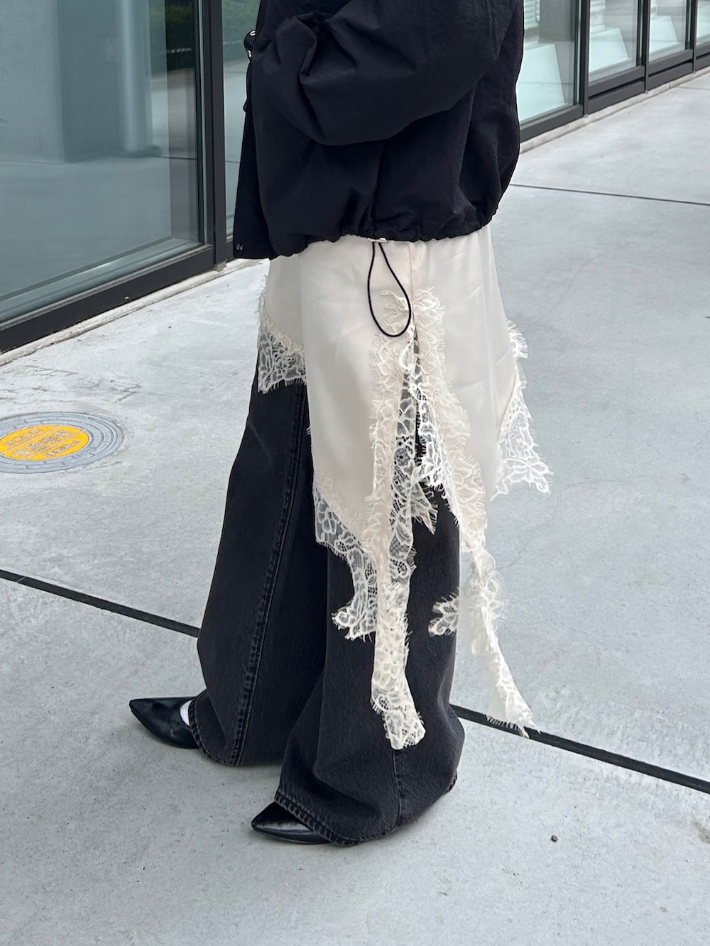 ホワイト系のキャミソール、ブラック系のナイロンジャケット、ブラック系のパンプスを着用したレディースの春コーディネートの2枚目の写真